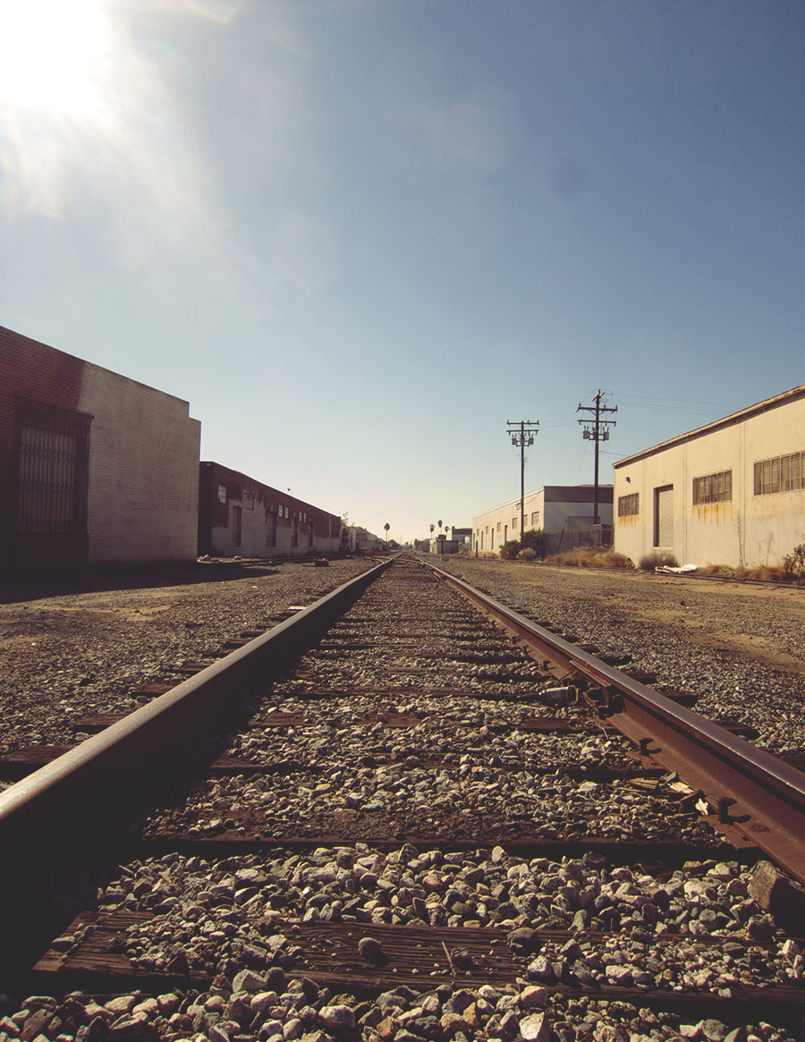 Train tracks surrounded by warehouse buildings.